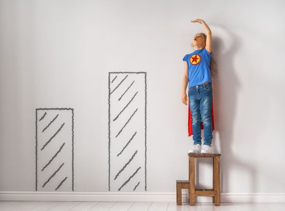 Boy standing on a chair measuring his height, and checking how tall he wants to become.