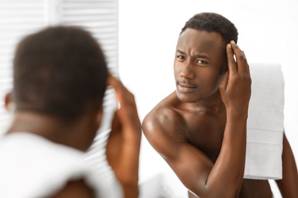 Man checking his hair in mirror looking for dandruff traces.