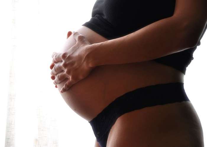 Woman fertility: pregnant woman expecting a baby soon, putting her hands on her belly.