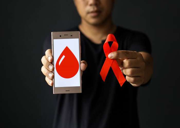 HIV AIDS awareness campaign. Woman holding phone with blood drop image representing AIDS, and ribbon for AIDS awareness.