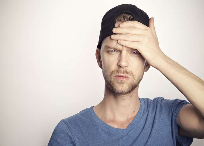 Man suffering from headache and migraine pain, putting his hand on his head.