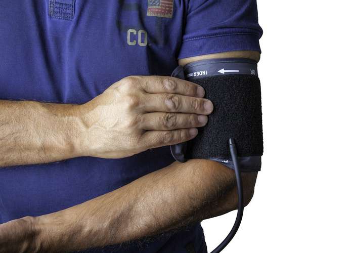 Person measuring his blood pressure by wrapping an inflatable cuff around the arm. The cuff starts to inflate gradually.