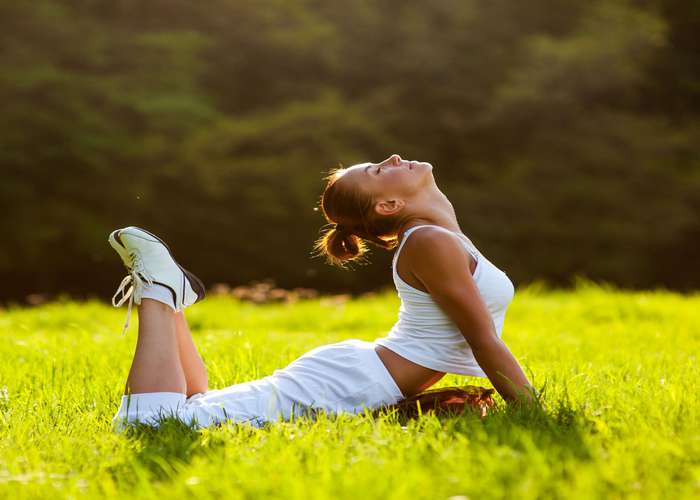 Woman in good health, laying on the grass, enjoying the weather and feeling good: Living better and healthier.