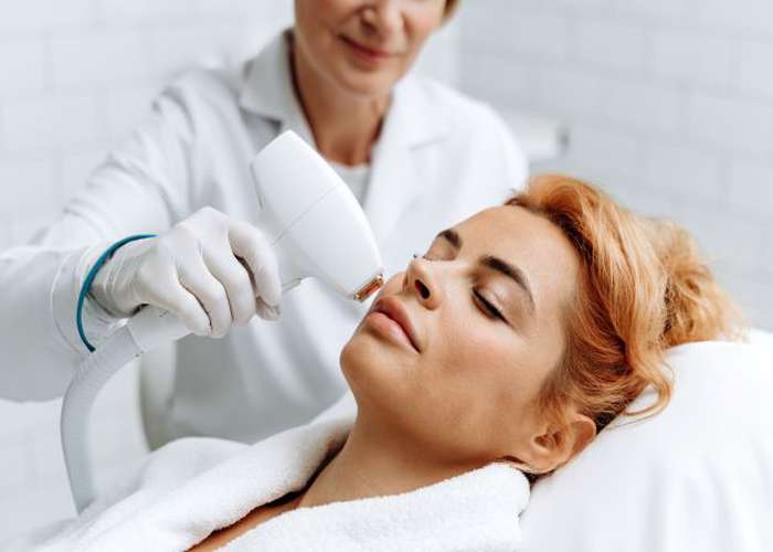 Laser therapy for acne scars. Woman doing a laser therapy session in a clinic to remove acne scars.