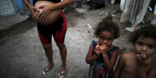 Patricia Araujo, who is seven-months pregnant, stands next to children as they pose in front of their stilt house, a lake dwelling also known as palafitte or ‘Palafito’, in Recife