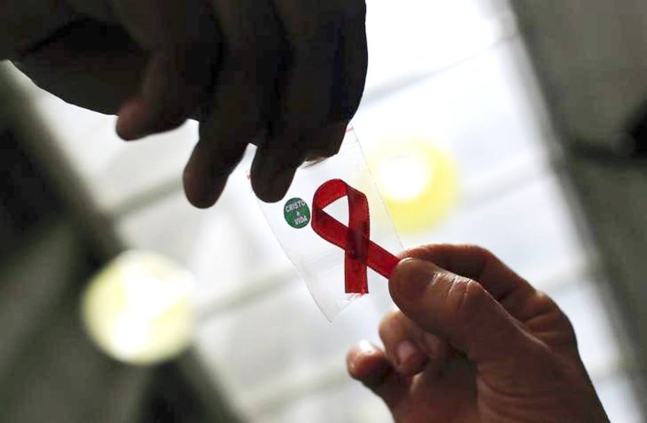 Nurse gives a red ribbon to a woman to mark World Aids Day at the entrance of Emilio Ribas Hospital, in Sao Paulo