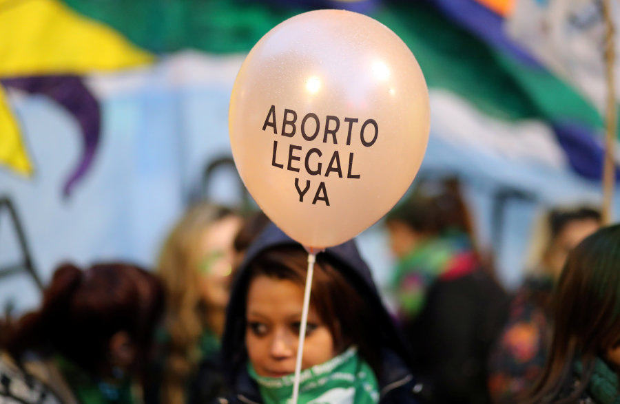 A demonstrator holds a baloon that reads “Legal abortion now” during a protest against femicides and violence against women in Buenos Aires