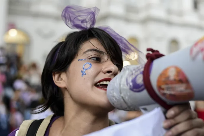 Mulher protesta com megafone contra machismo violência de gênero feminicídio e pede por igualdade. Foto Henry Milleo/Getty Images