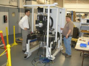 Engineer and assembler standing by beginning stages of a large machine's build