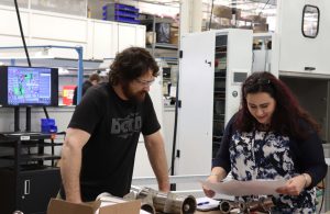 Assembler and engineer reviewing work instructions with computer station behind them