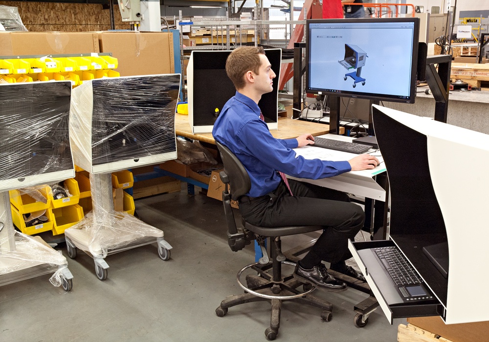 Engineer reviewing drawings on manufacturing floor with 3 machines on wheels