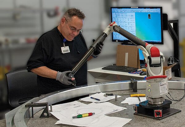 Quality Inspector using hand held device, Romer Arm, to inspect a medical machinery part 