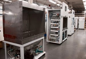 Three white machines in different stages of production