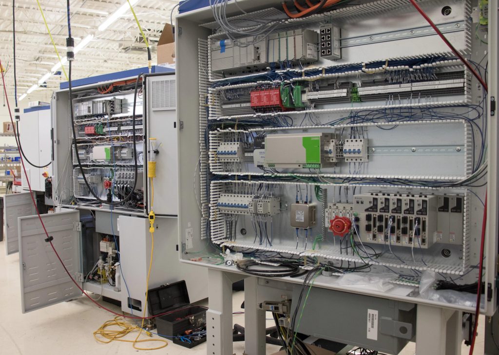 Three machines in production showing electrical assembly in the back of machines