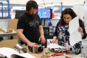 Engineers reviewing mechanical hardware and technical drawings during product development