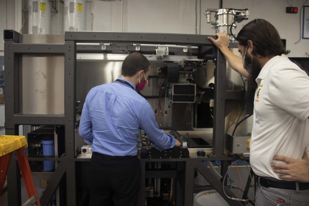 Engineers analyzing a machine's prototype build on the manufacturing floor to review DFMA