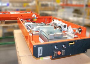 Warehouse automation pallet shuttle assemblies with mechanical drives, electrical components, and fabricated structures staged for final equipment build.