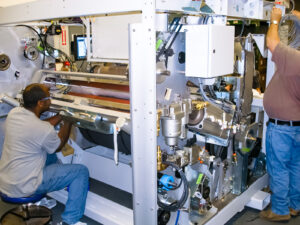 Two men assembling custom automation equipment for the printing industry in PEKO's state-of-the-art NPI contract manufacturing facility.