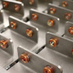 Rows of sheet metal brackets with installed fasteners, showing precision hardware assembly for structural applications.