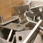Press brake forming of precision sheet metal hardware brackets with holes and fasteners, used in structural assemblies.