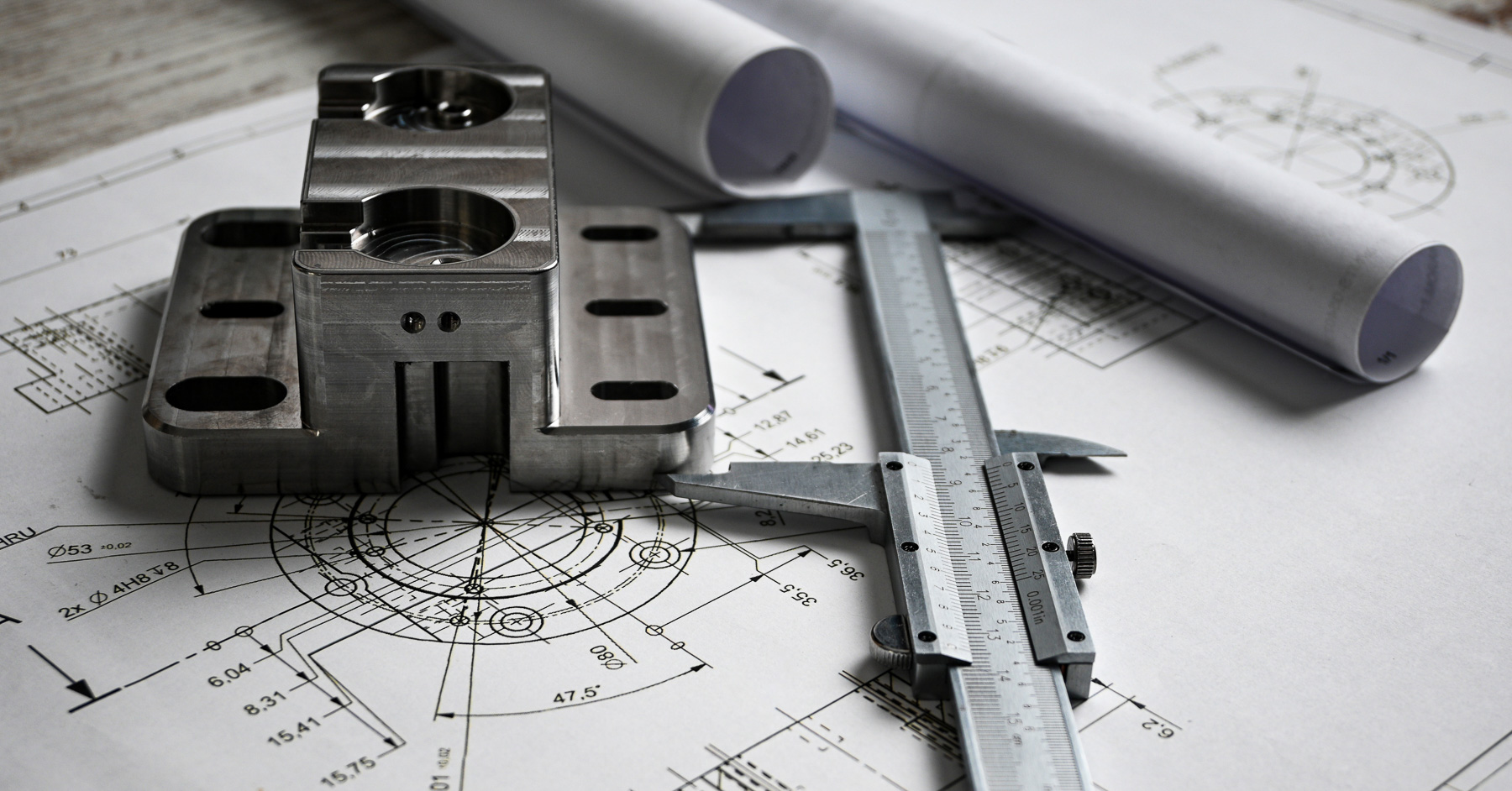 Machined metal component on engineering drawings with calipers, showing the reverse engineering process for mechanical parts and CAD documentation.
