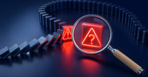 Magnifying glass highlighting a warning symbol in a falling domino chain representing product development risk