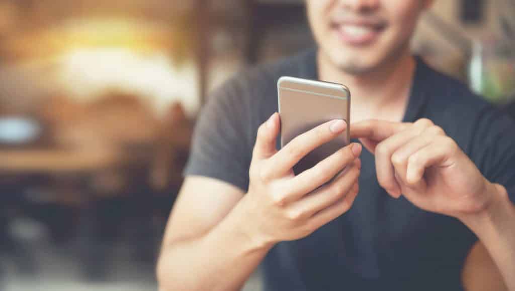 Happy man using smartphone at modern coffee shop, he chatting Online Messaging on mobile phone. copy space