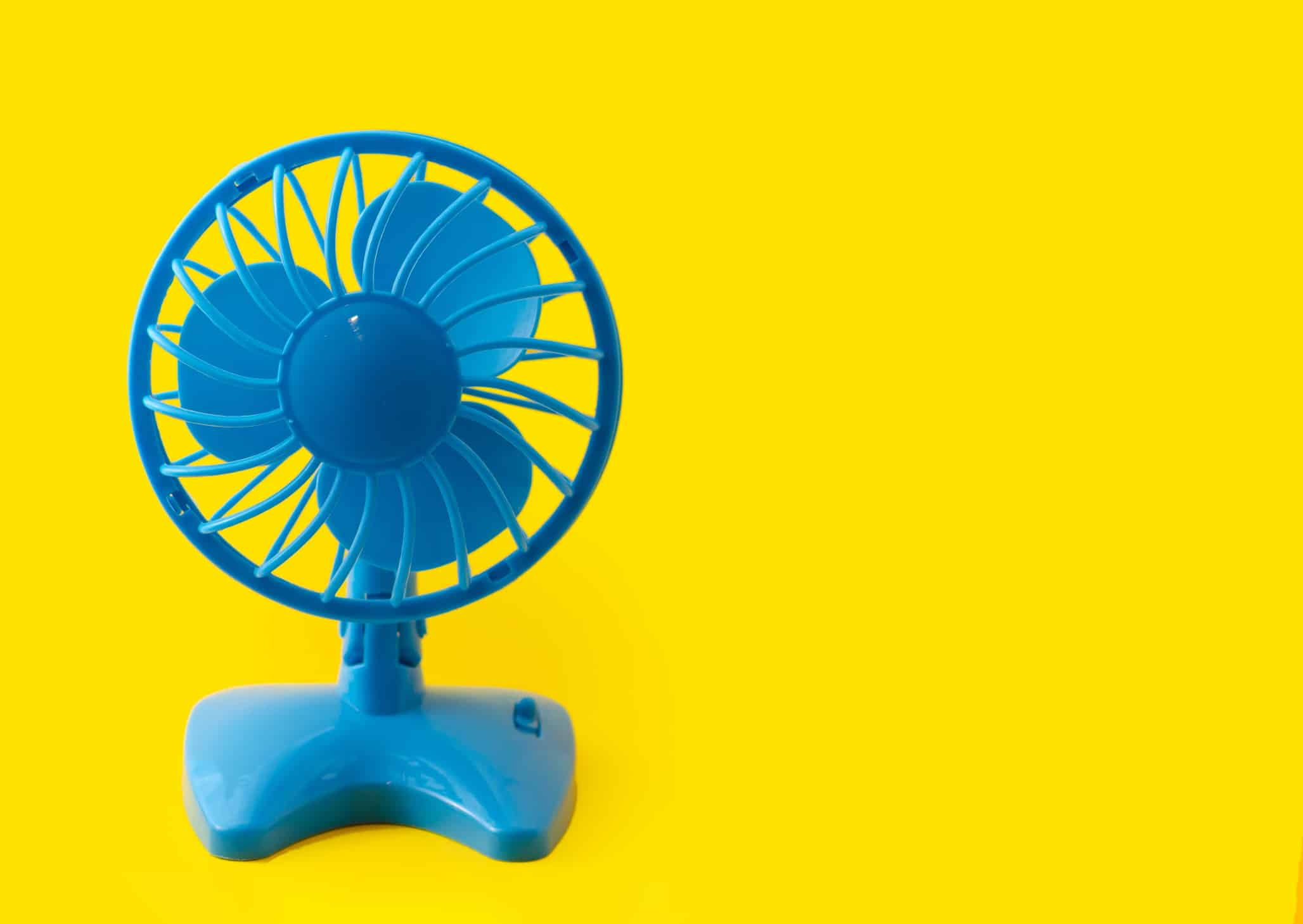 electric blue plastic fan isolated on yellow background