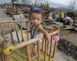 Un niño descansa entre los escombros de las casas dañadas por el paso del tifón Nock-Ten por la localidad de Polangui, provincia de Albay (Filipinas). EFE