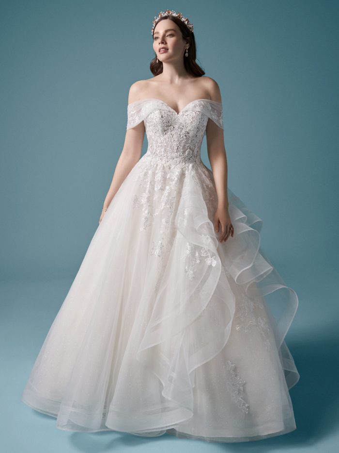 Model Wearing Off-the-Shoulder Ball Gown Wedding Dress with Horsehair Hem Called Zariah by Maggie Sottero