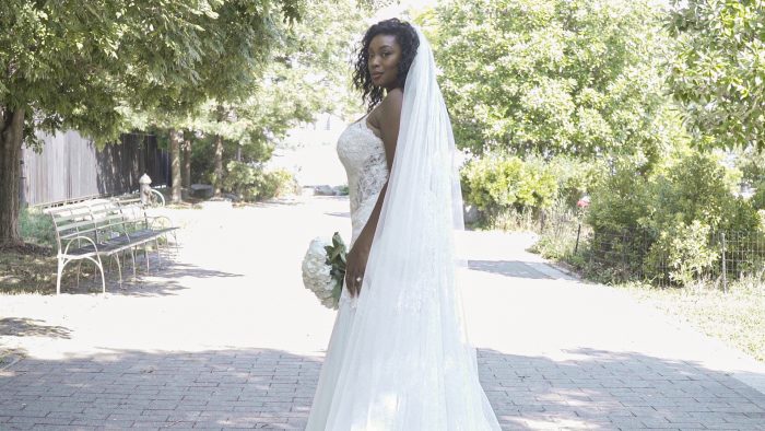 Plus Size Model Wearing Strapless Curvy Wedding Dress with Veil Called Halle by Maggie Sottero