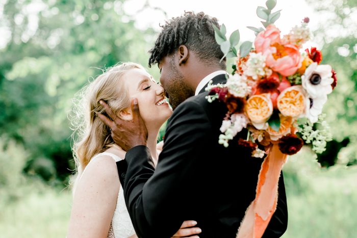 Bride and Groom Kissing While Bride Holds Bohemian Wedding Bouquet