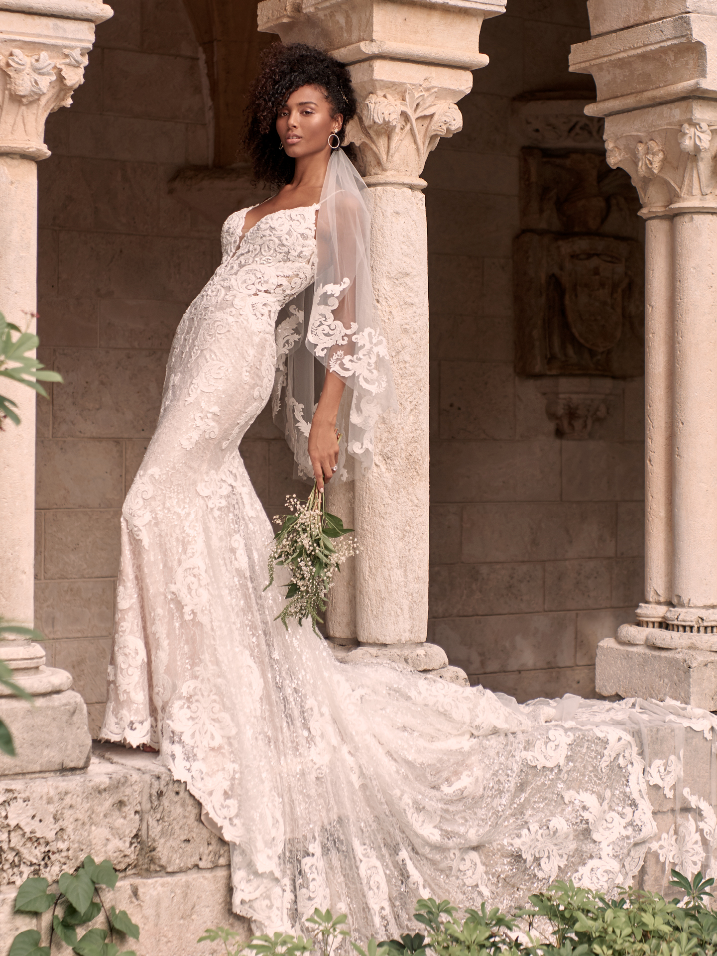 Black Model Wearing Sparkly Lace Sheath Bridal Gown with Extended Train Called Tuscany Royale by Maggie Sottero