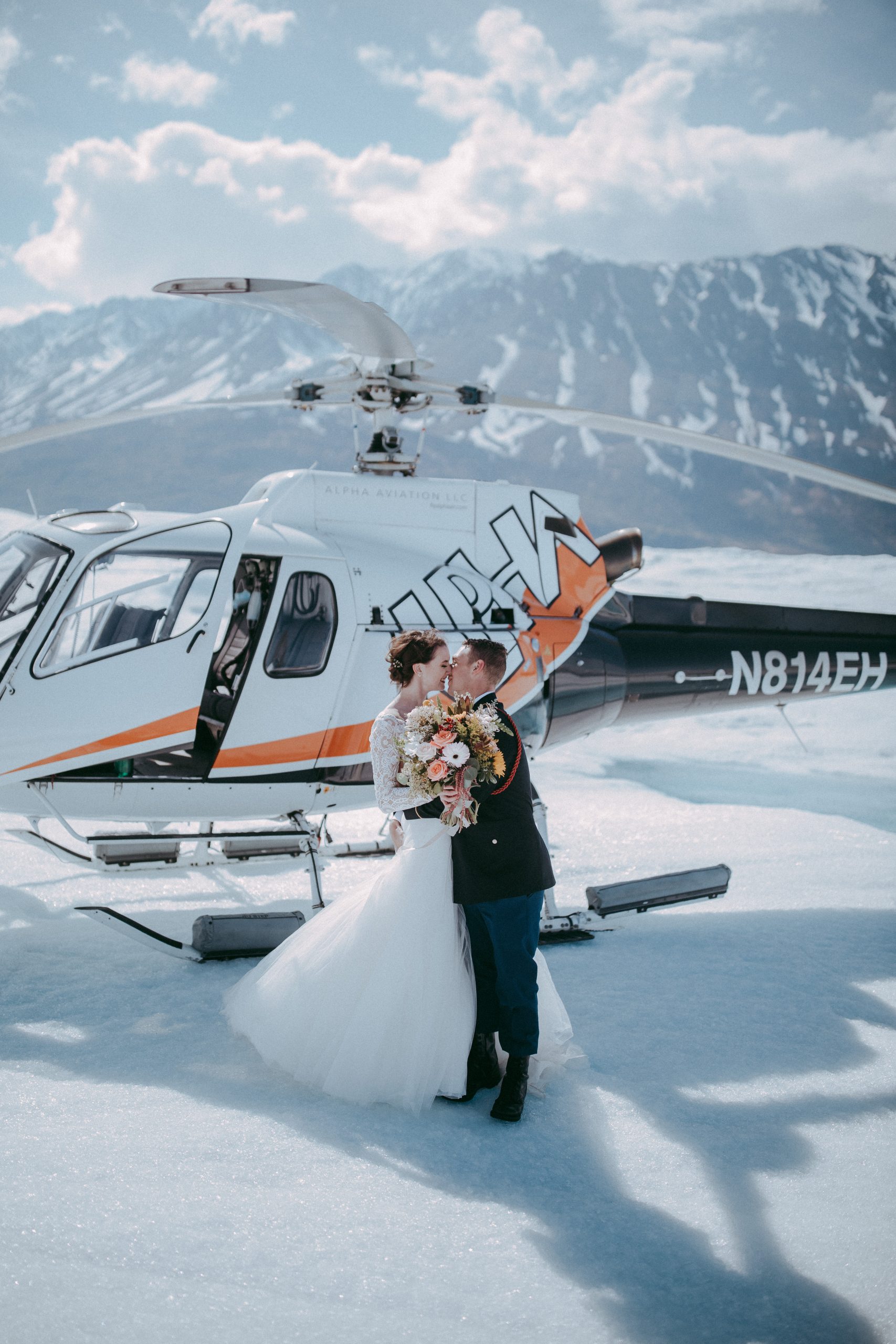 Groom with Real Bride Getting Married on Glacier in Alaska in Romantic Destination Wedding with Helicopter Behind Them