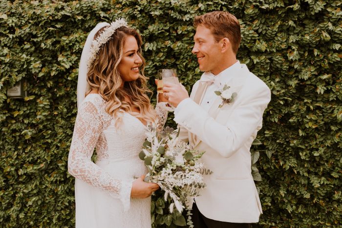 Bride and Groom Drinking from Each Other's Wine Glasses at Boho Wedding