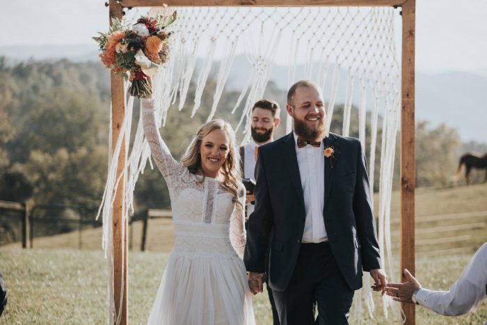 Groom with Real Bride at Boho Festival Wedding Walking Away from Rustic Wedding Arch