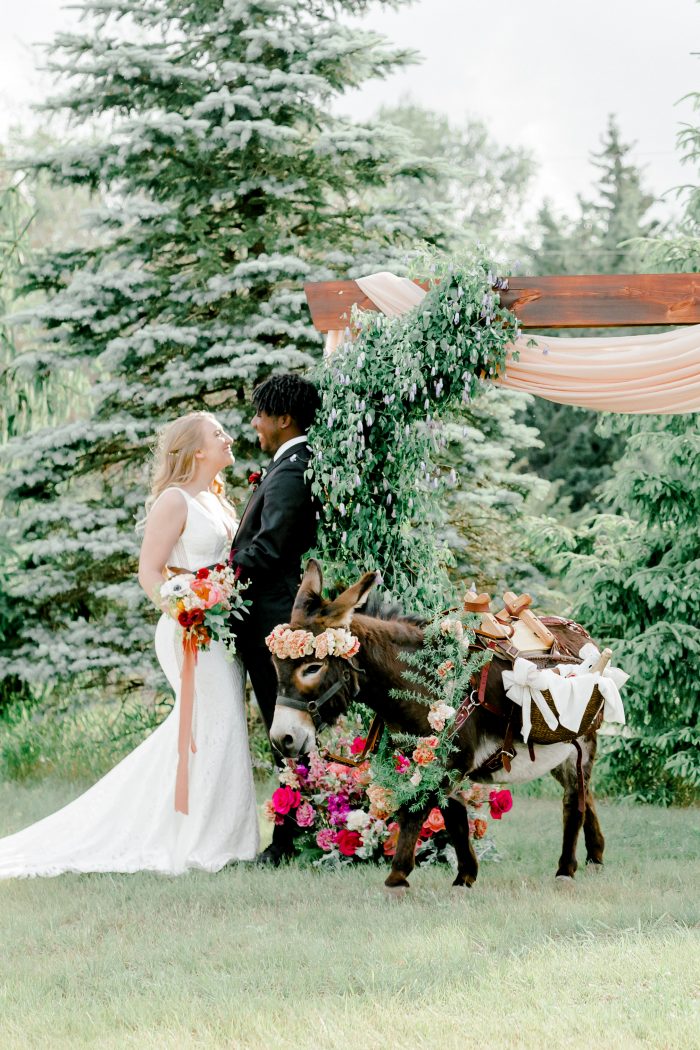 Bride and Groom at Intimate Wedding Ceremony with Colorful Florals and Unique Donkey under an Archway