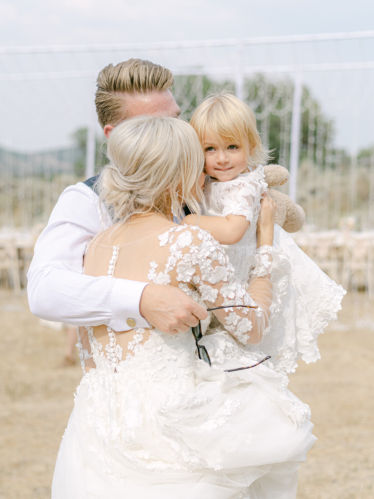 Bride Kissing Groom and Her Daughter While Wearing Custom Maggie Sottero Wedding Dress with Illusion Bishop Sleeves
