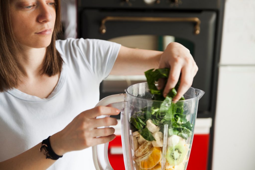 lady making a smoothie with a blender