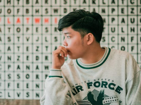 thoughtful young ethic guy touching lips and looking away