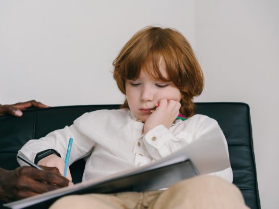 bored boy holding colored pencils