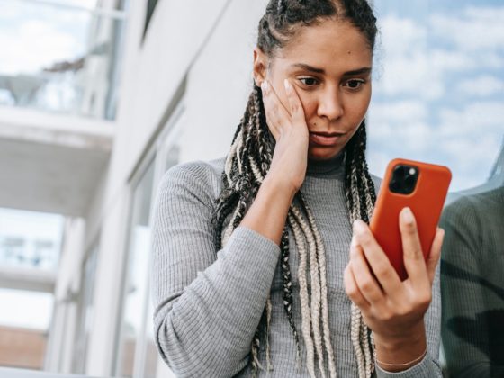 crop concerned black woman using smartphone on street