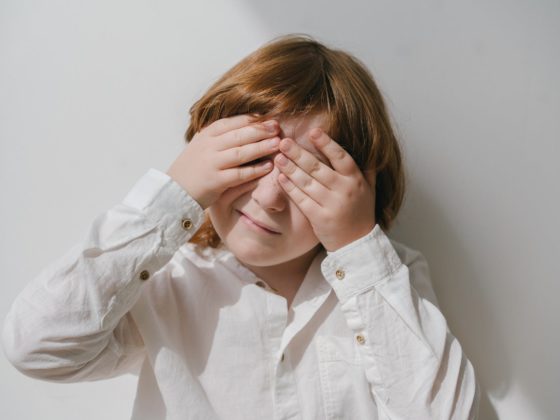 photograph of a boy covering his eyes