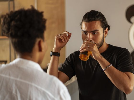 man standing in front of woman and drinking beer