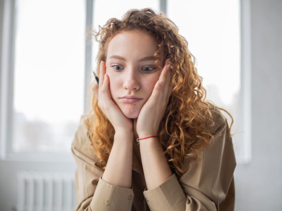 puzzled woman with pen studying in room