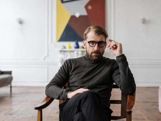 man in black sweater sitting on brown wooden chair