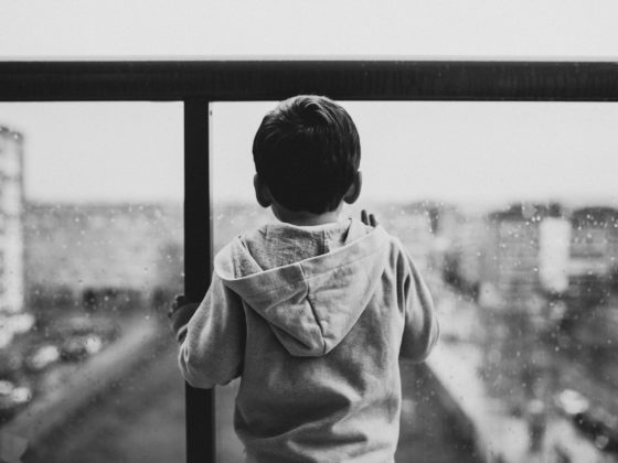 backview of sad child waiting on a glass window