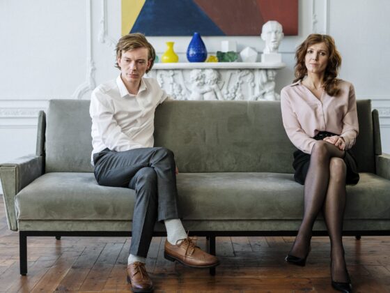woman in white dress shirt and black pants sitting on gray couch