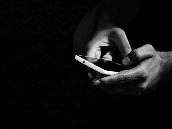 grey scale photo of person holding smartphone