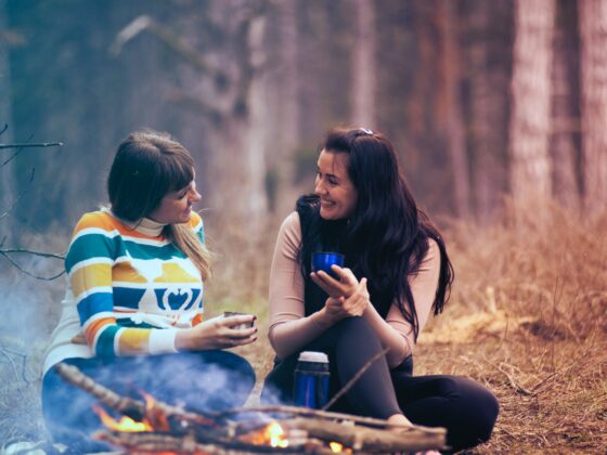 two women sitting on ground near bonfire